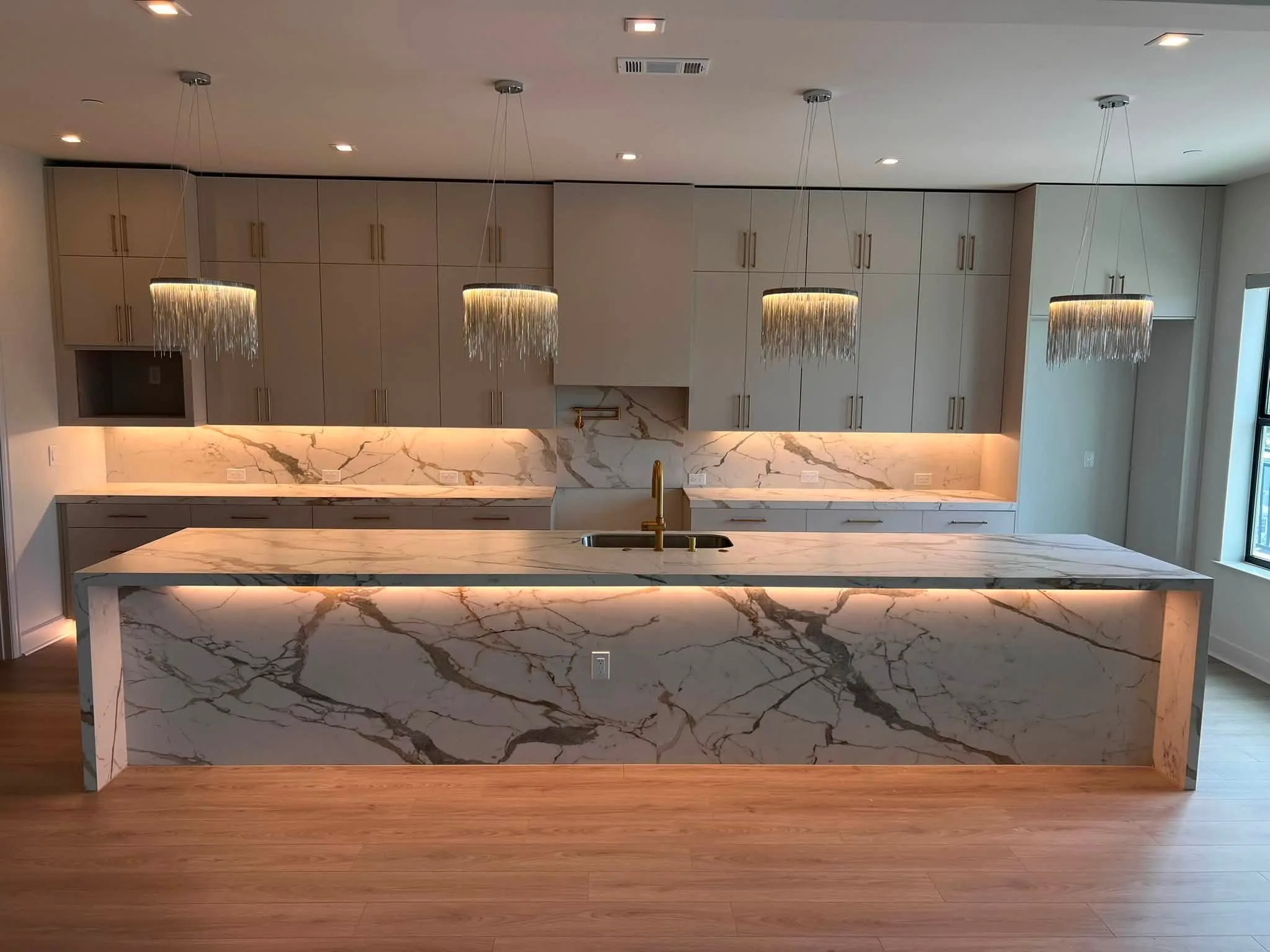 Porcelain waterfall island with a full-height slab backsplash, from Omega Marble & Granite